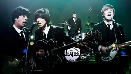 The Upbeat Beatles performing dressed in match black suits, white shirts and black ties. 