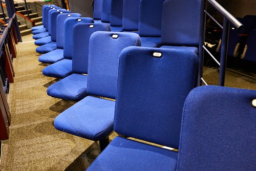 blue seats to the side of the auditorium, angled towards the stage