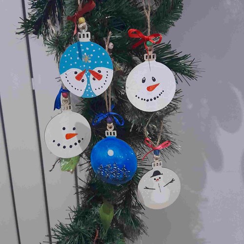 Hand crafted snowmen bauble baubles hanging from a Christmas tree