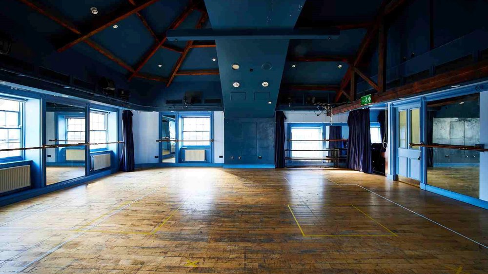 Our Attic Theatre, a large room with blue walls and wooden floor with lots of natural light. An ideal space for rehearsals and workshops.