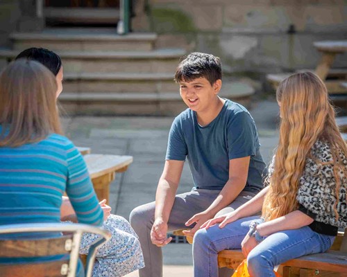 A group of young people sitting and chatting in the courtyard of Lawrence Batley Theatre.