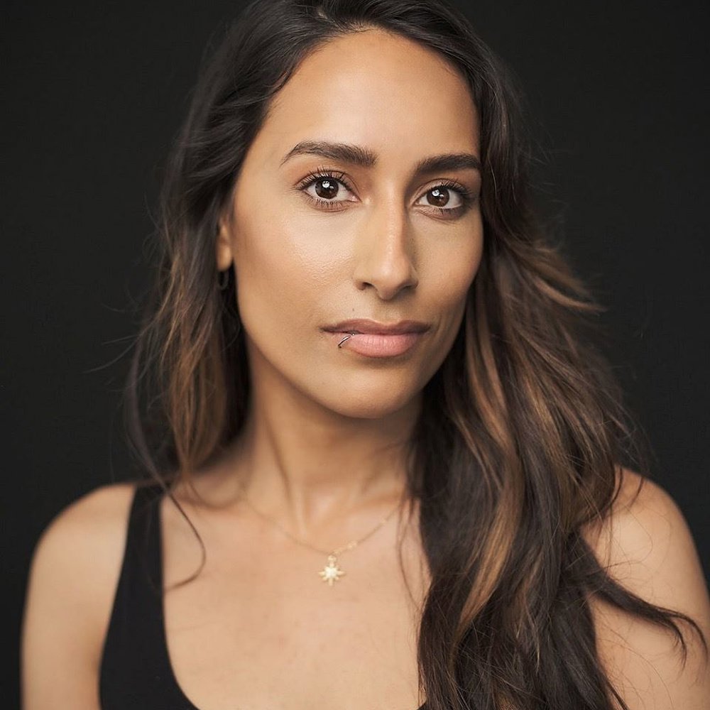 Headshot of Sonia Wrightson. She has long wavy hair, wears a black tank top, and looks directly at the camera with a slight smile.