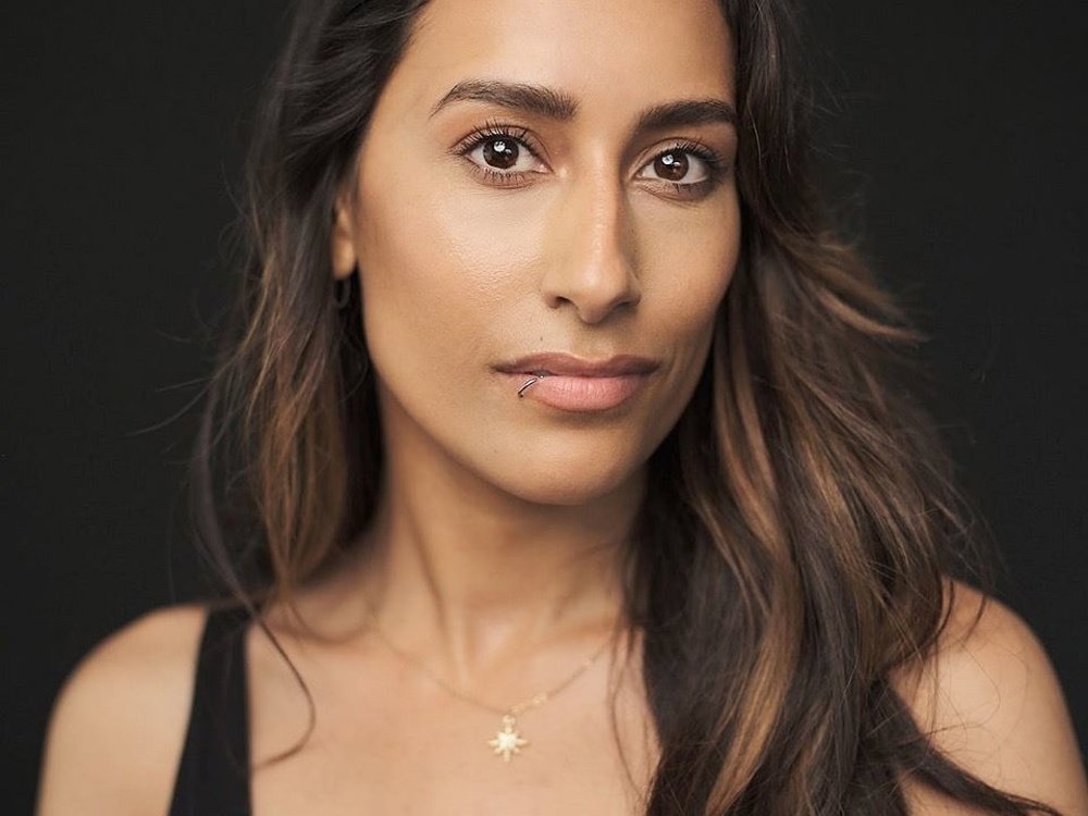 Headshot of Sonia Wrightson. She has long wavy hair, wears a black tank top, and looks directly at the camera with a slight smile.