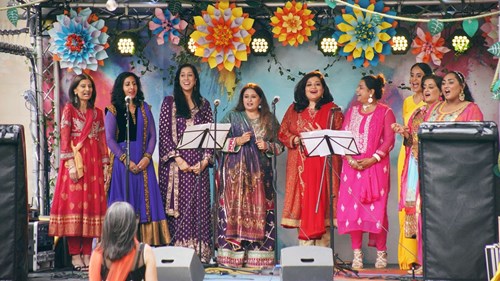 Group of women of South Asian heritage, singing together in brightly coloured dress
