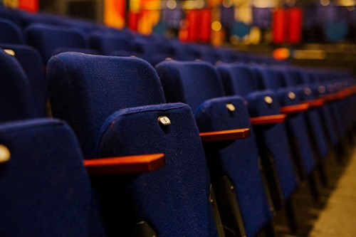A row of dark blue flip-up seats with wooden armrests.