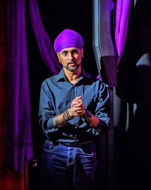 Hardeep Sahota in front of a purple backdrop, wearing a purple turban, grey shirt and blue jeans