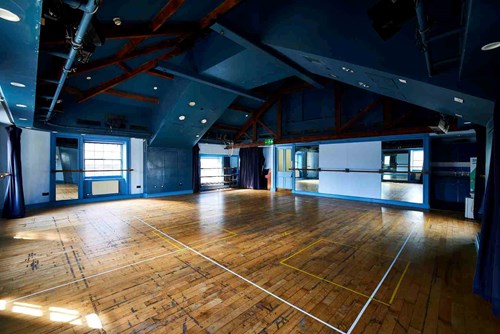 Our Attic Theatre, a large room with blue walls and wooden floor with lots of natural light. An ideal space for rehearsals and workshops.
