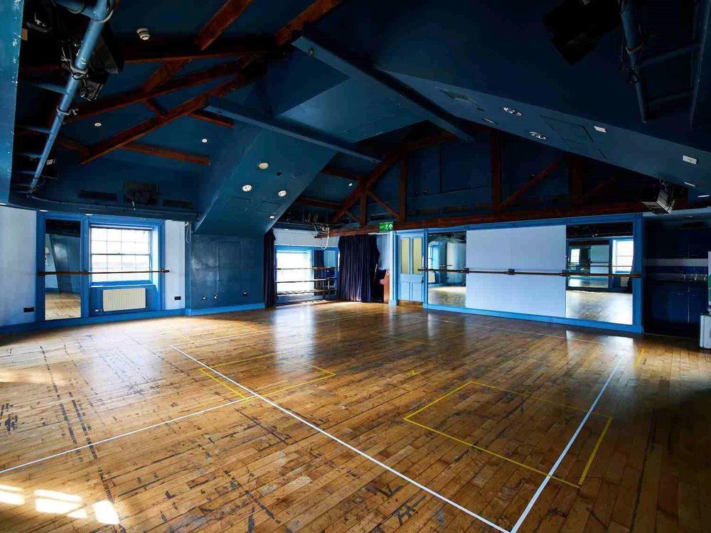 Our Attic Theatre, a large room with blue walls and wooden floor with lots of natural light. An ideal space for rehearsals and workshops.