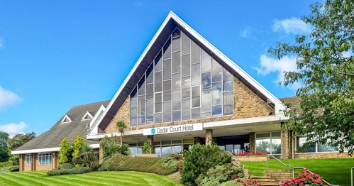 Picture of the front of Cedar Court Hotel Huddersfield, with a large pitch roof and big windows on a sunny day