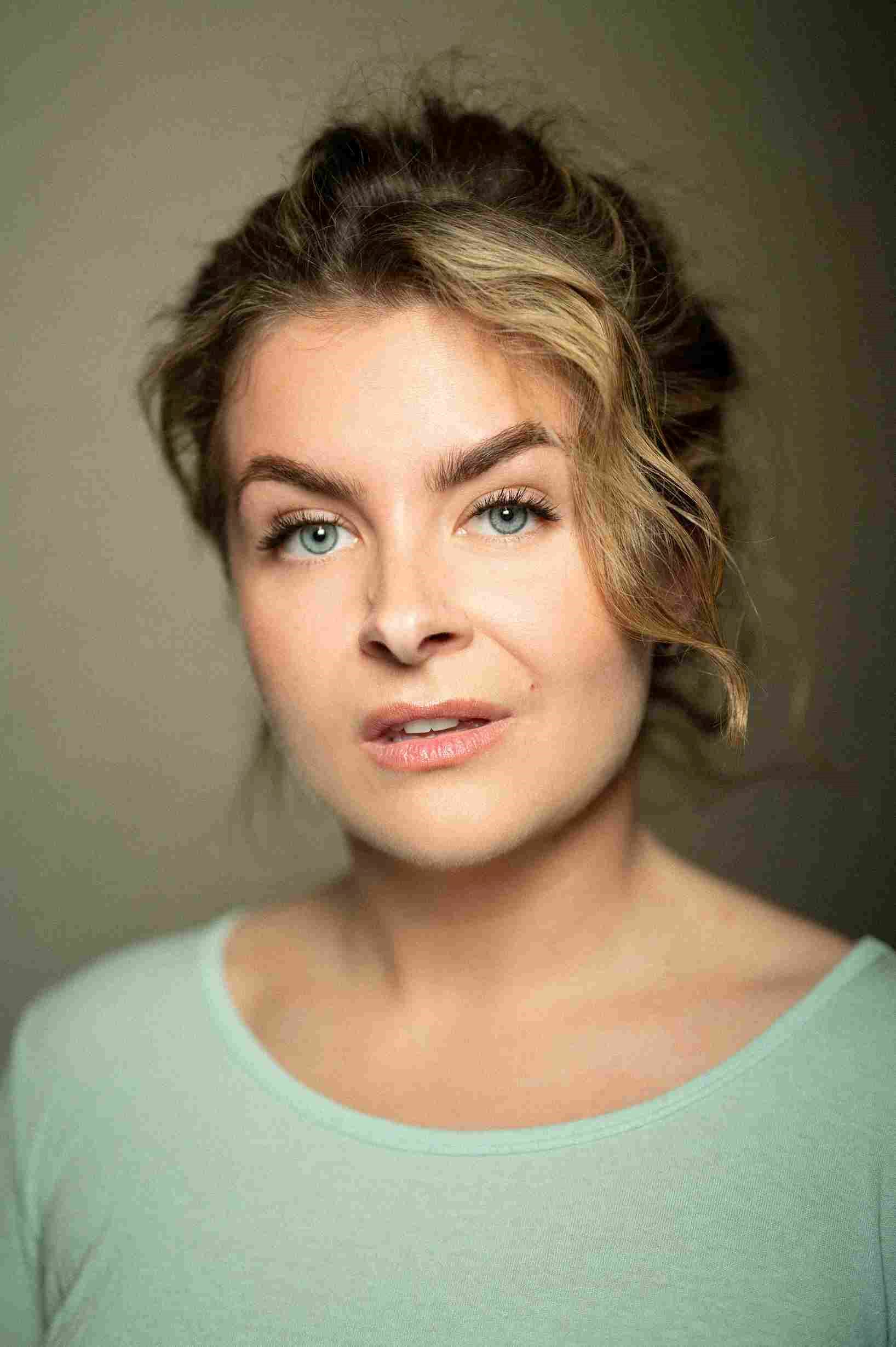 Shady Murphy: Woman with light eyes and wavy hair loosely tied back, wearing a light green top, looking confidently at the camera.