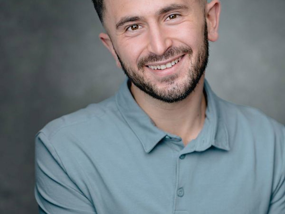 Headshot of Thomas Cotran. He has short dark hair, wears a light blue polo shirt, and smiles warmly at the camera.