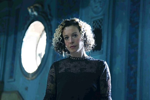 Kate Rusby pictured with brown curly hair and two bleach blond highlights and wearing a black dress. 