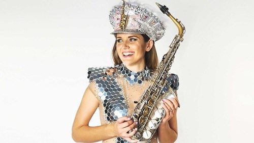 Photo of Ellie Sax wearing sequins carrying her saxophone