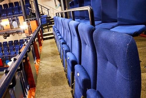 blue seats upstairs, first row angled in towards the audience, second row angled towards the stage
