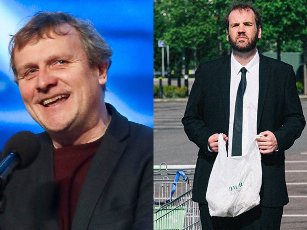 Split-screen promotional image featuring two comedians. On the left, a smiling performer speaks into a microphone on stage against a blue-lit background. On the right, a bearded performer in a black suit and tie stands in a supermarket car park holding a plastic shopping bag, with trees and parked cars in the background.